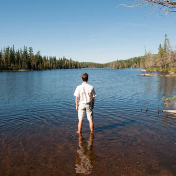 Man standing in water relaxing and contemplating wildness of lake superior provincial park, Canada.