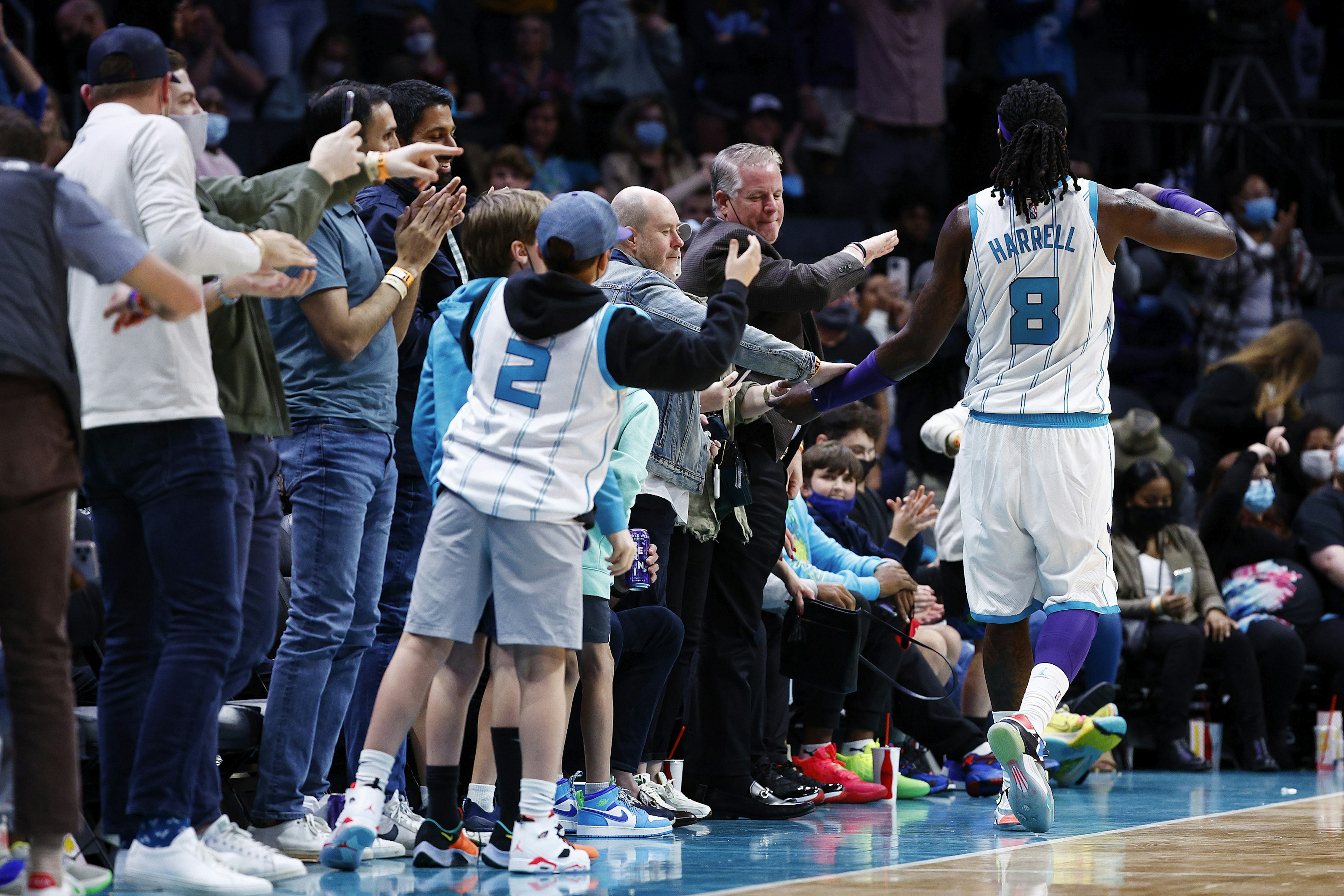 A Charlotte Hornets NBA player high-fives fans as he runs down the court during a game in Charlotte.