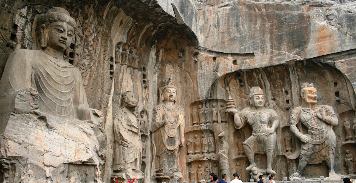 Luoyang, China - June 19, 2008: Tourists take photos in front of the massive stone carvings of Buddha at the Longmen Grottoes.
