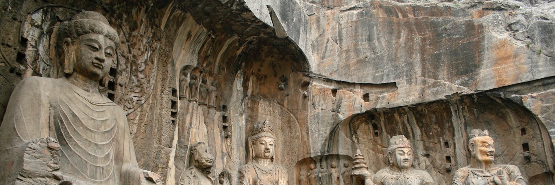 Luoyang, China - June 19, 2008: Tourists take photos in front of the massive stone carvings of Buddha at the Longmen Grottoes.