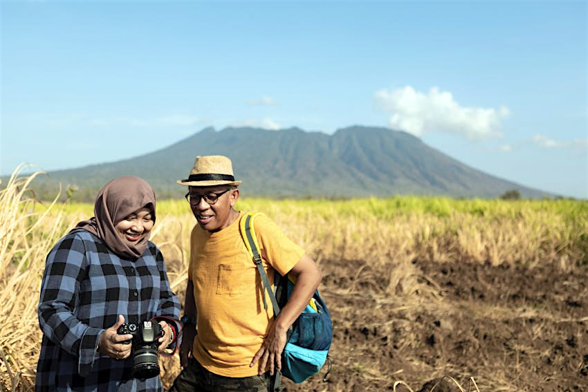 Pasangan pendaki melihat foto mereka setelah trekking di Taman Nasional Baluran