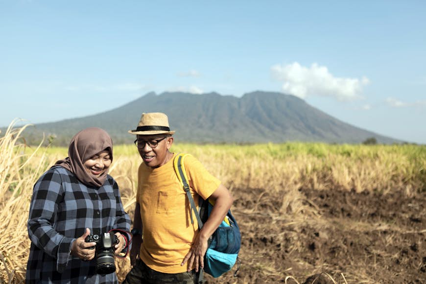 Hiking couple looking their photographs after trekking in Baluran National Park