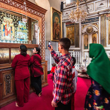 El-Qusiya, Egypt - November 4th, 2011: A Coptic family visits a shrine at Deir al-Muharraq monastery also called the Burned Monastery. Being one of the oldest functioning monasteries in the world it is an important pilgrimage place for Coptic Christians. Deir Al Muharraq monastery