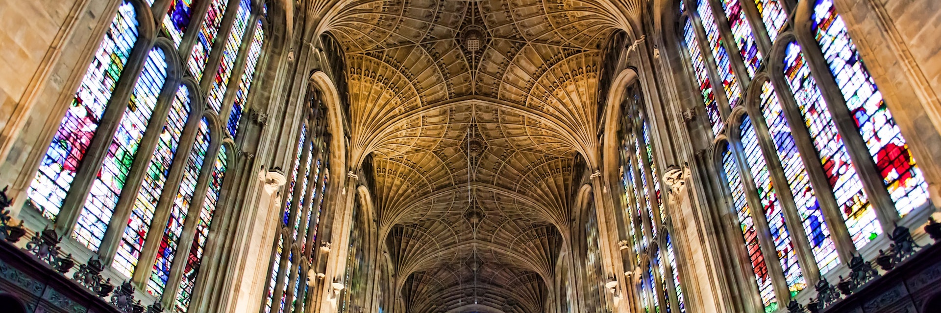 View inside Kings college Chapel Cambridge, showing the fan vault ceiling and vast wooden paneling, and amazing stain glass windows.