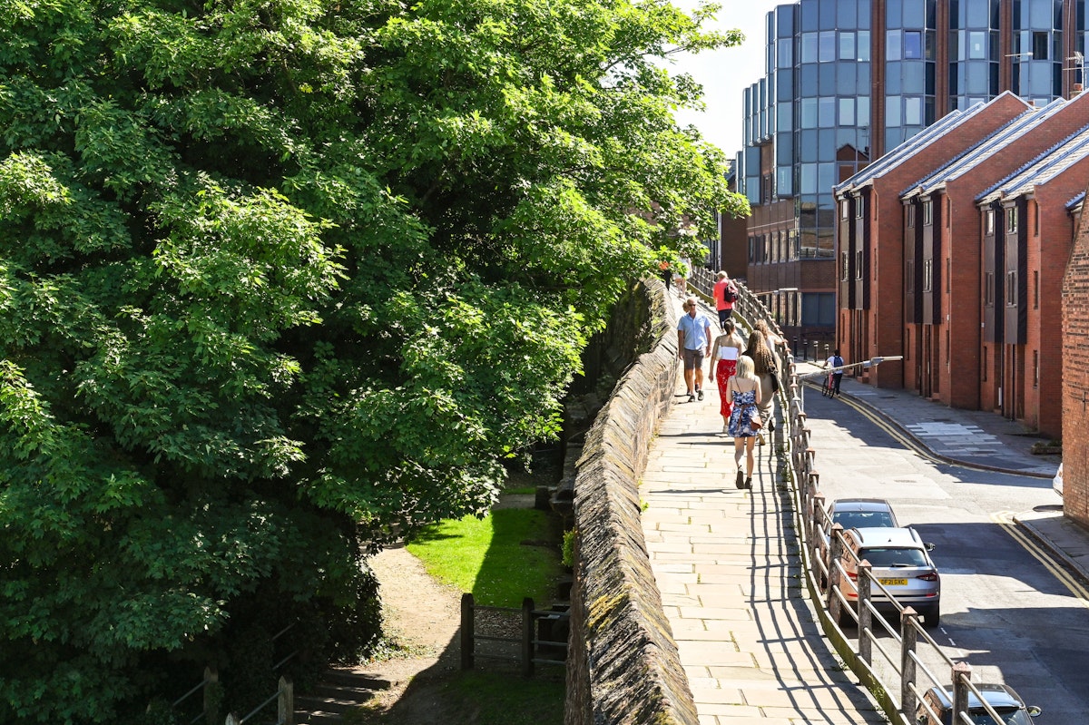 Chester, England - July 2021: Visitors walking on an elevated section of  the walk around the city's old wall.