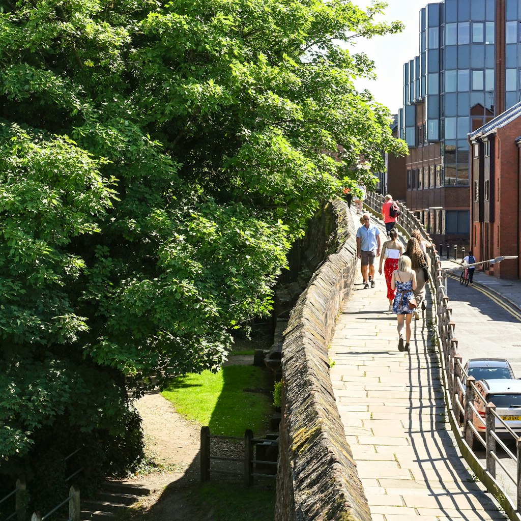 Chester, England - July 2021: Visitors walking on an elevated section of  the walk around the city's old wall.