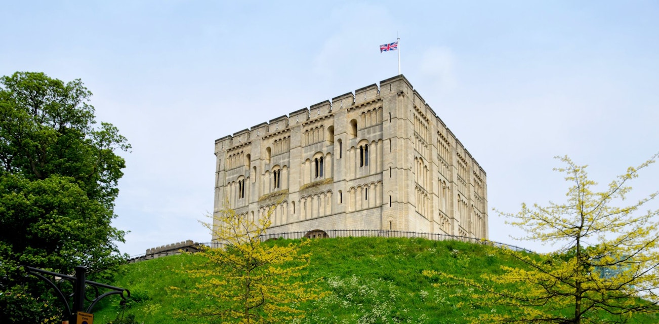 "Norwich, England - May 17, 2012: A man walking past Norwich Castle keep and castle mound on a spring day. The stone keep was constructed by order of the King between 1100 and 1120 to replace a wooden structure which stood on the same mound dating back to the Norman conquest of 1066. The castle was used as a prison until 1887 and has been used as a museum since 1894."