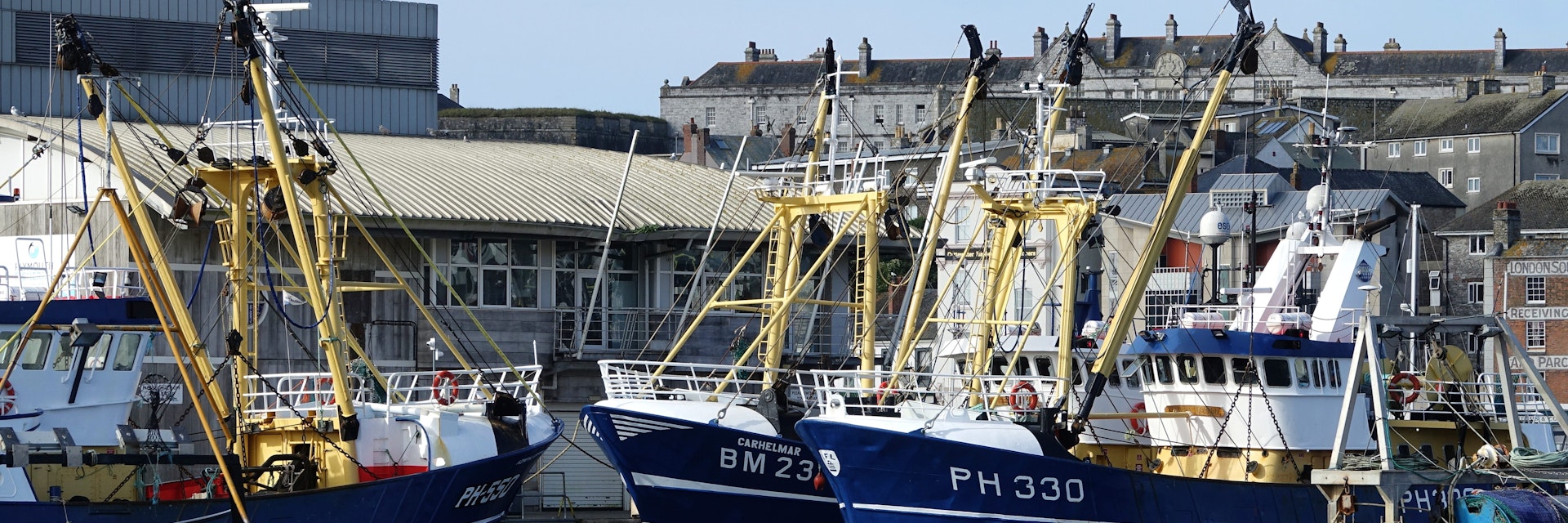 Plymouth England August 2020.  The fish market with the deep sea fishing fleet moored alongside the quay. Boats registered in Plymouth and Brixham. Light cloud