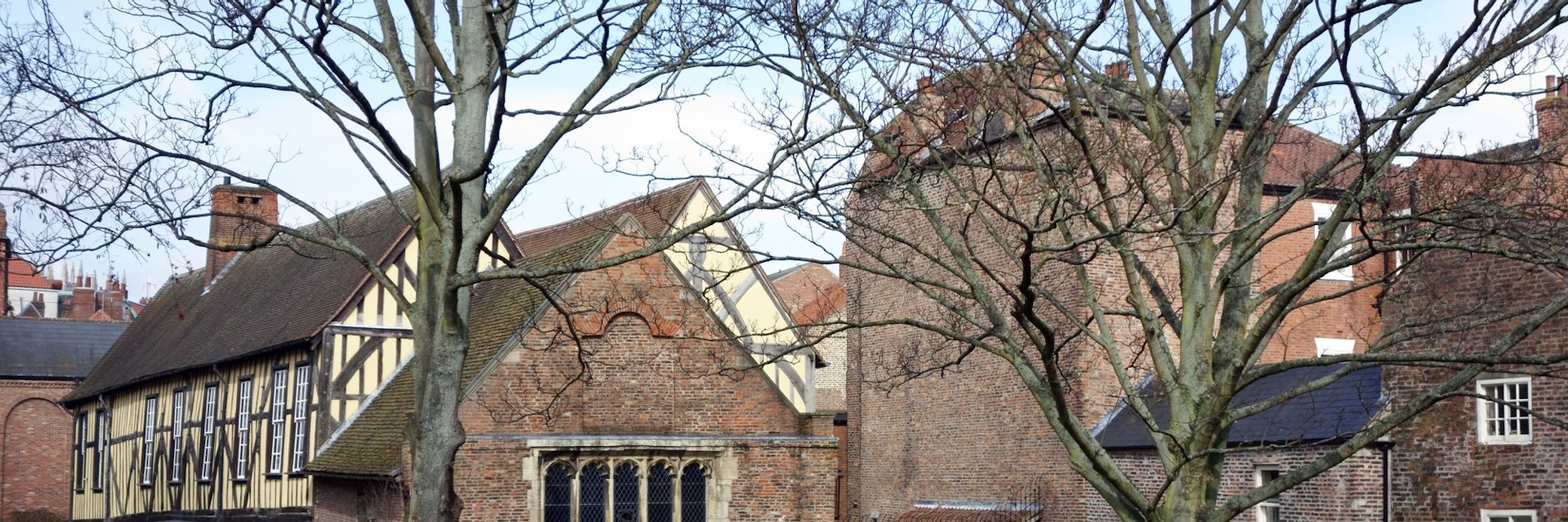 York, UK - February 19, 2013: Merchant Adventurers Hall was constructed in the fourteenth century and is still in use today. An senior couple is strolling in the grounds and tow men in the background are picking up litter.