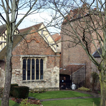 York, UK - February 19, 2013: Merchant Adventurers Hall was constructed in the fourteenth century and is still in use today. An senior couple is strolling in the grounds and tow men in the background are picking up litter.