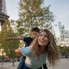 Happy mother and son traveling to Paris and playing to be on a plane near the Eiffel Tower