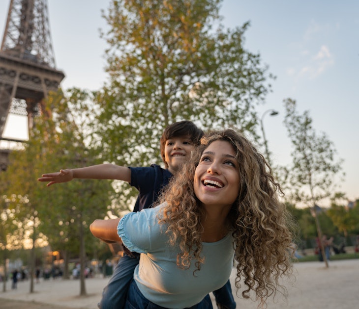 Happy mother and son traveling to Paris and playing to be on a plane near the Eiffel Tower
