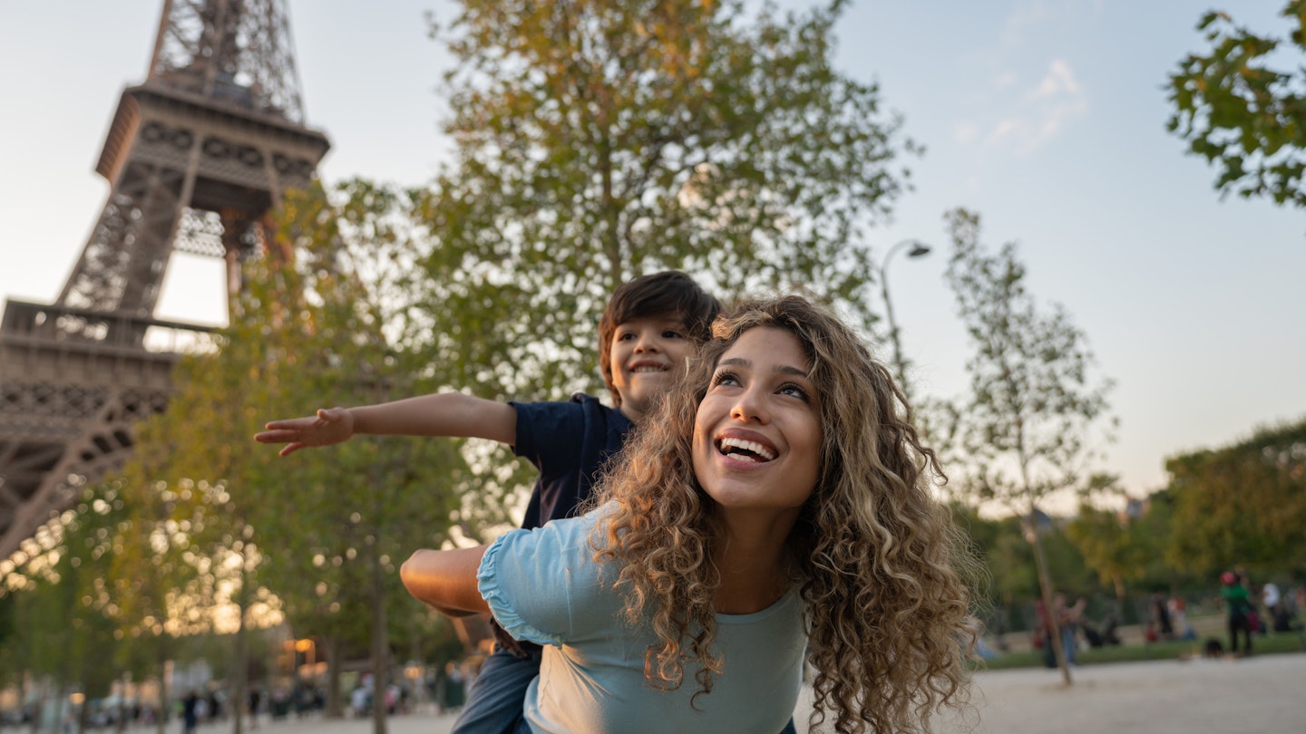 Happy mother and son traveling to Paris and playing to be on a plane near the Eiffel Tower