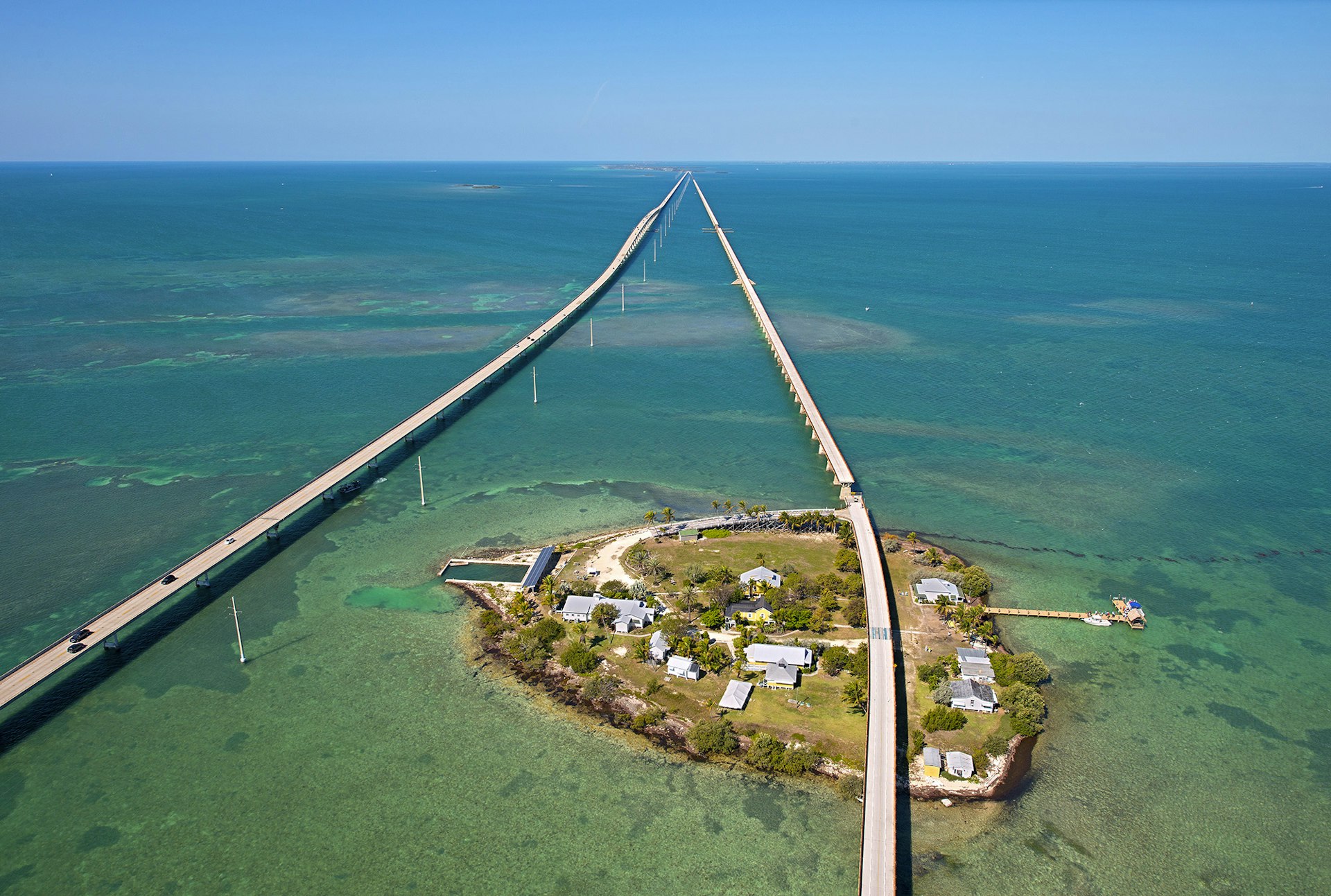 An aerial view of Pigeon Key in turquoise waters, with the new and old Seven Mile Bridges on either side 