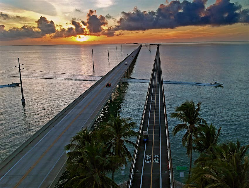 Drone aerial photo of boats passing underneath the new and old Seven Mile bridges at sunset in the Florida Keys