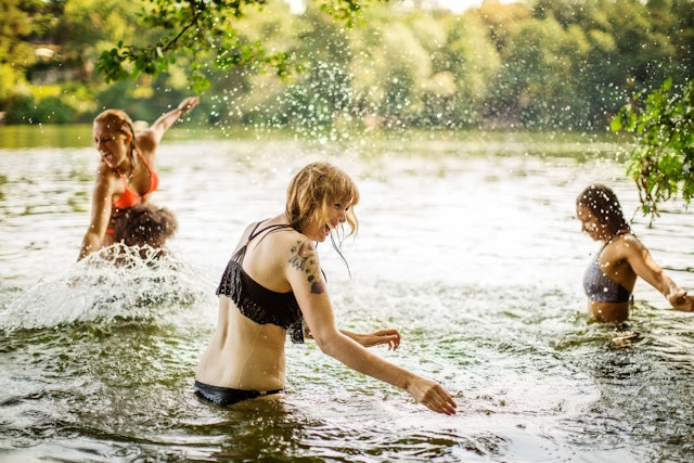 Female friends having fun swimming in a lake in summer