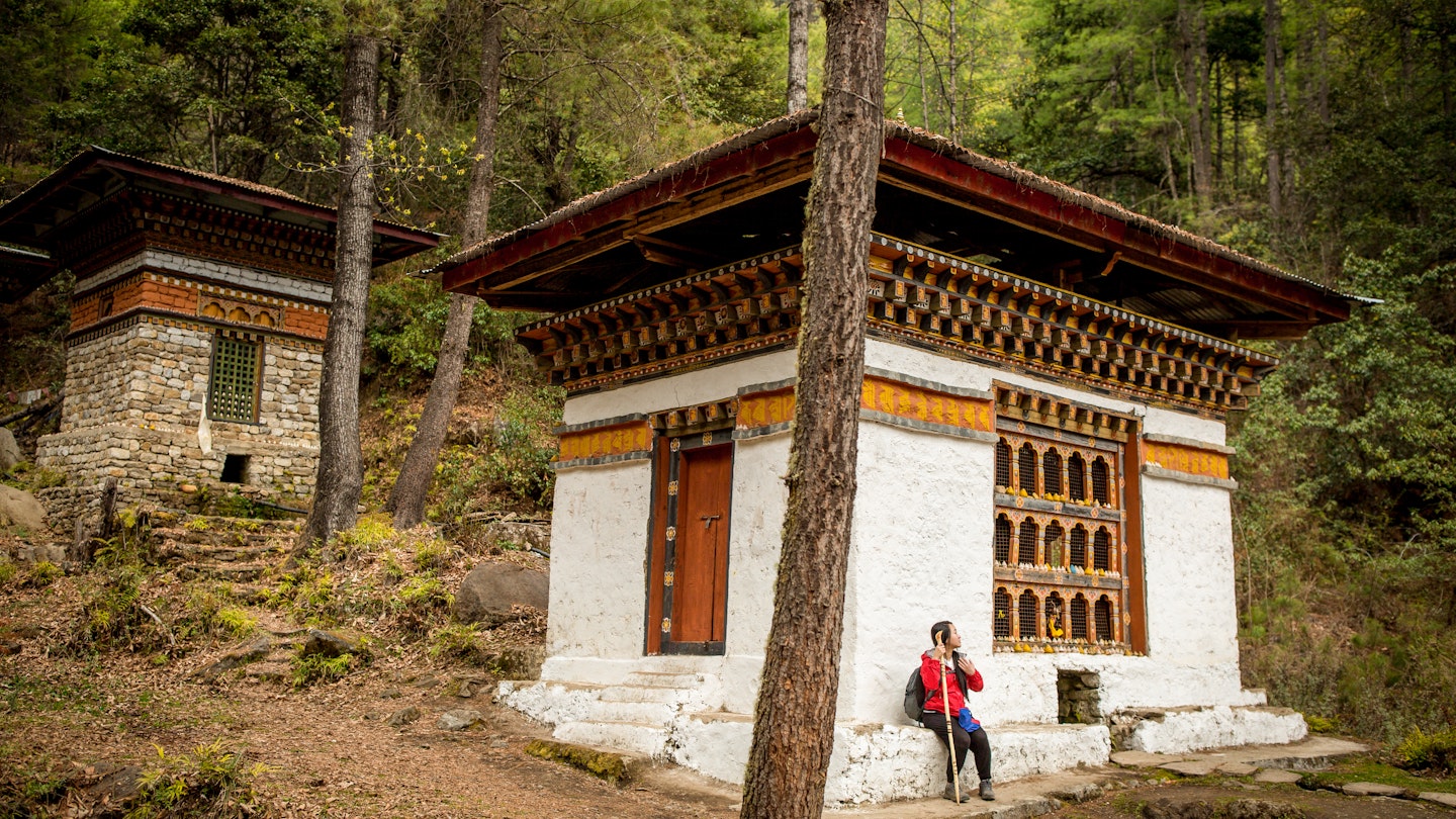 A Woman Outside Tiger's Nest Monastery in Paro, Bhutan Springtime
A young woman, wearing hiking gear, stands outside Tiger's Nest monastery, also known as Paro Taktsang, located 900m up on a cliffside in the valley town of Paro, Bhutan. Tiger's Nest monastery, constructed in 1692, was built around the cave where Guru Rinpoche first meditated. Shot on a bright spring afternoon.