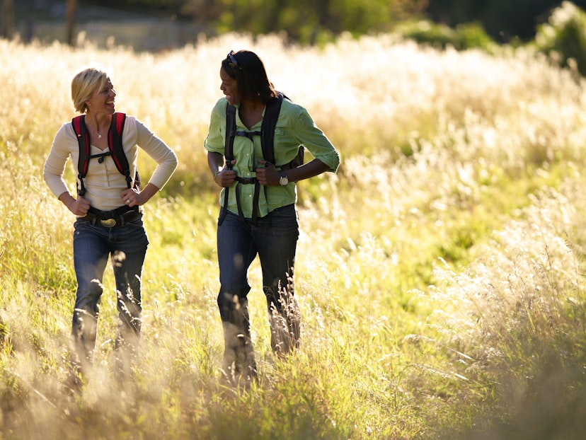 Two women hiking through a grassy meadow in Colorado