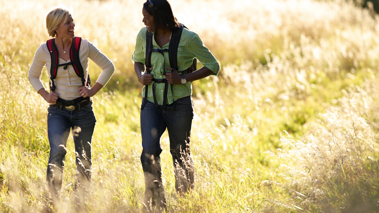 Two women hiking through a grassy meadow in Colorado