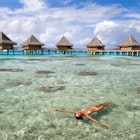Woman floating and sunbathing near tropical resort bungalows in rangiroa, Tahiti, French Polynesia.
