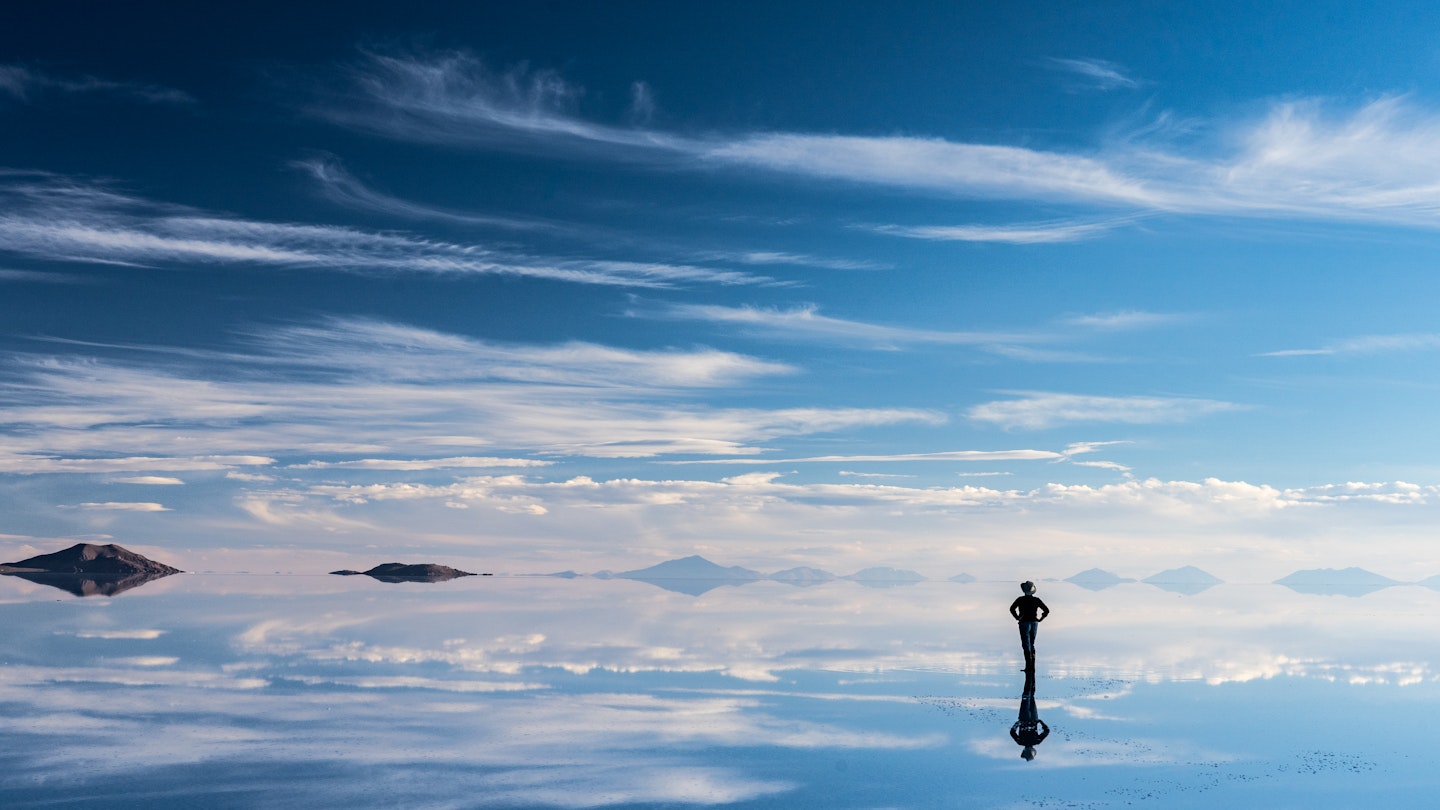 A traveler reflected in the mirror surface of the Salar de Uyuni salt flats