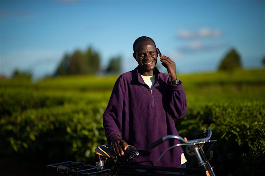 Smiling with a bicycle looking at camera talking on a mobile phone in a rural setting, Malawi