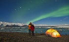 A camping couple gazes out at the northern lights