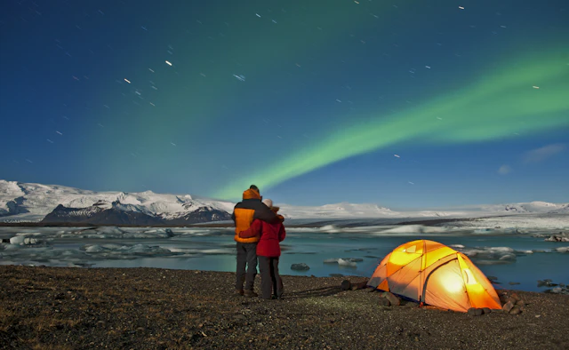 A camping couple gazes out at the northe lights