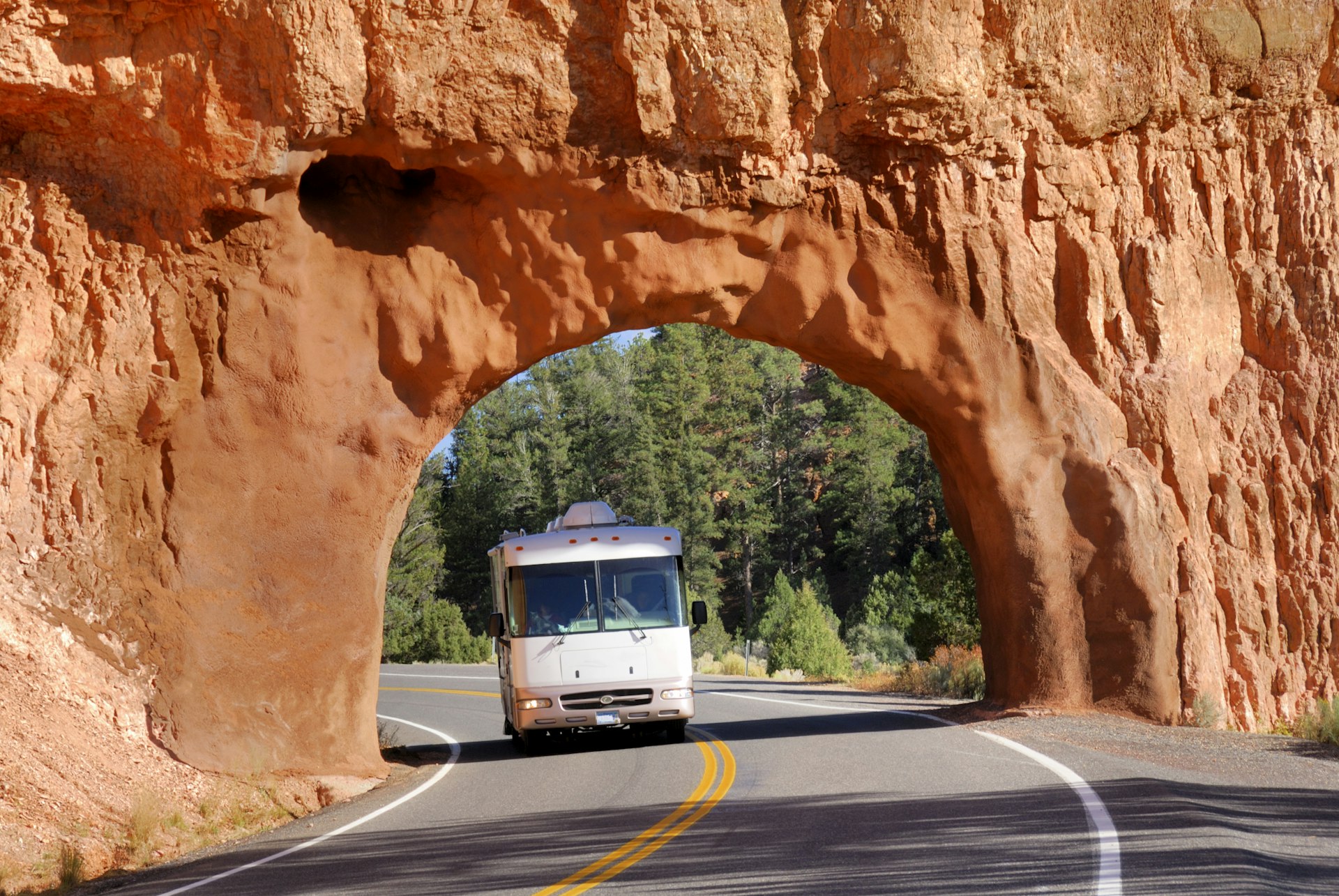 A motor home makes its way through a red arch in Bryce Canyon National Park, on its way to Arches National Park