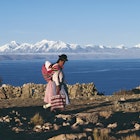 A Bolivian woman walking in front of Lake Titicaca