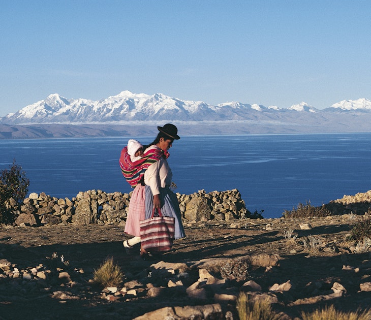A Bolivian woman walking in front of Lake Titicaca