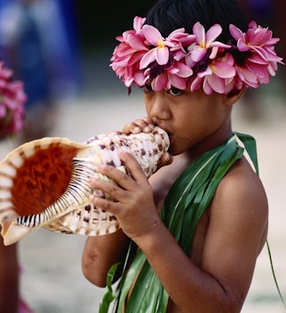 A young Cook Islander blowing a conch horn