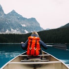 Rearview of an adult woman paddling canoe, Moraine Lake, Banff National Park, Alberta Canada