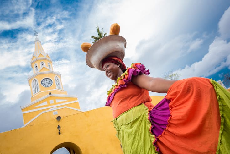 A palenquera woman in brightly colored dress selling fruits in Cartagena, Colombia
