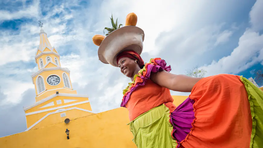 A palenquera woman in brightly colored dress selling fruits in Cartagena, Colombia