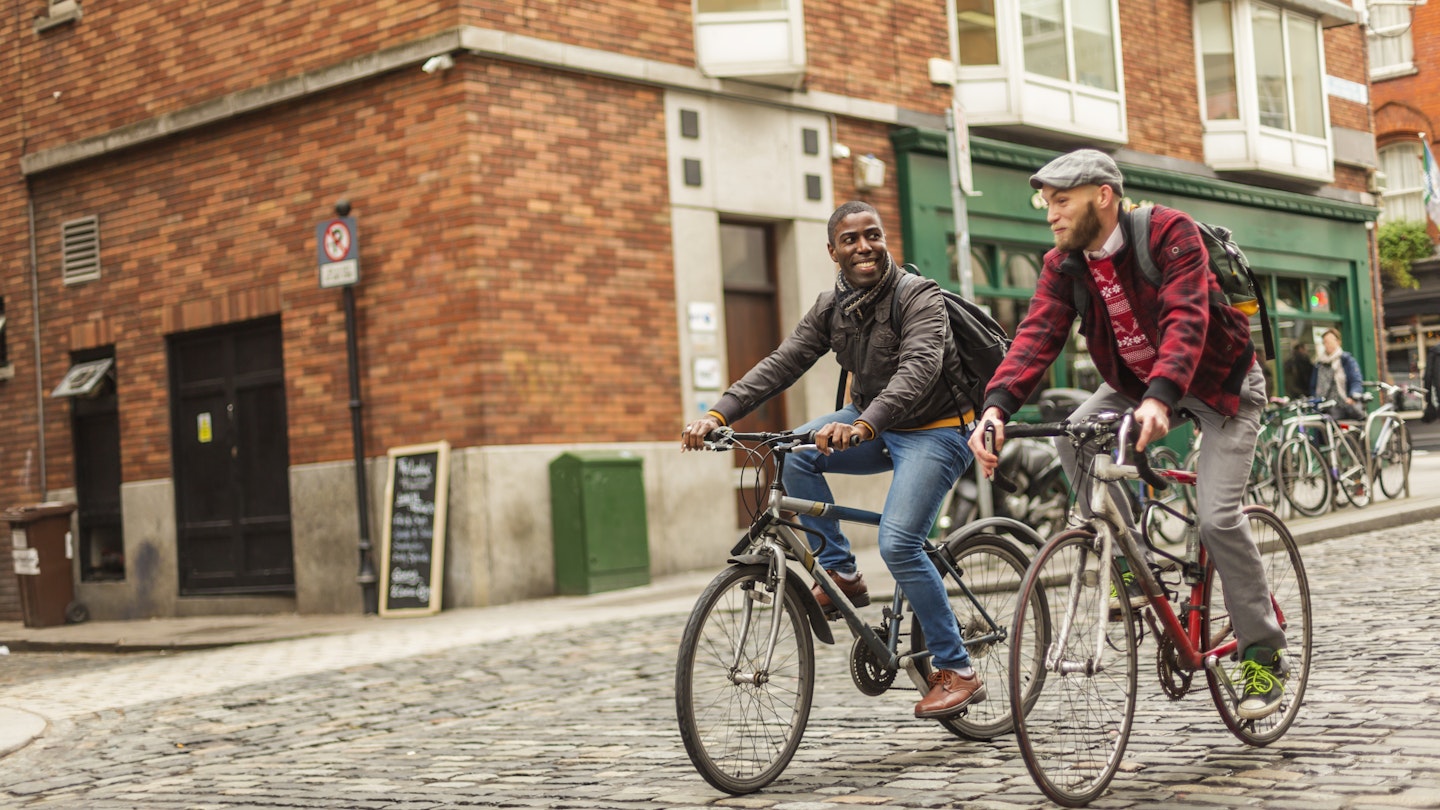 Mixed race gay men with bicycles in the city in the Temple Bar district of Dublin, Ireland
