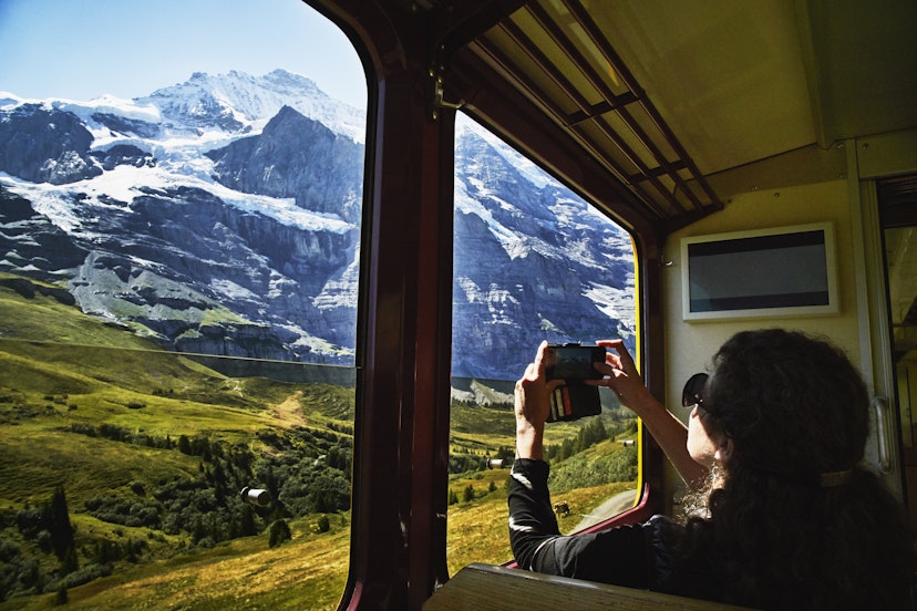 Woman taking photo with a smartphone of Jungfrau while riding in train