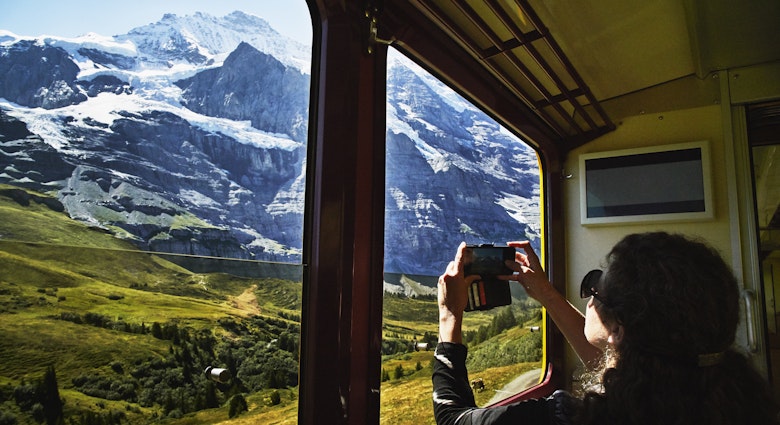Woman taking photo with a smartphone of Jungfrau while riding in train