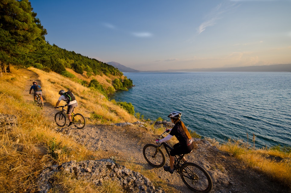 Three mountain bikers on a singletrack above lake Ohrid in Macedonia.