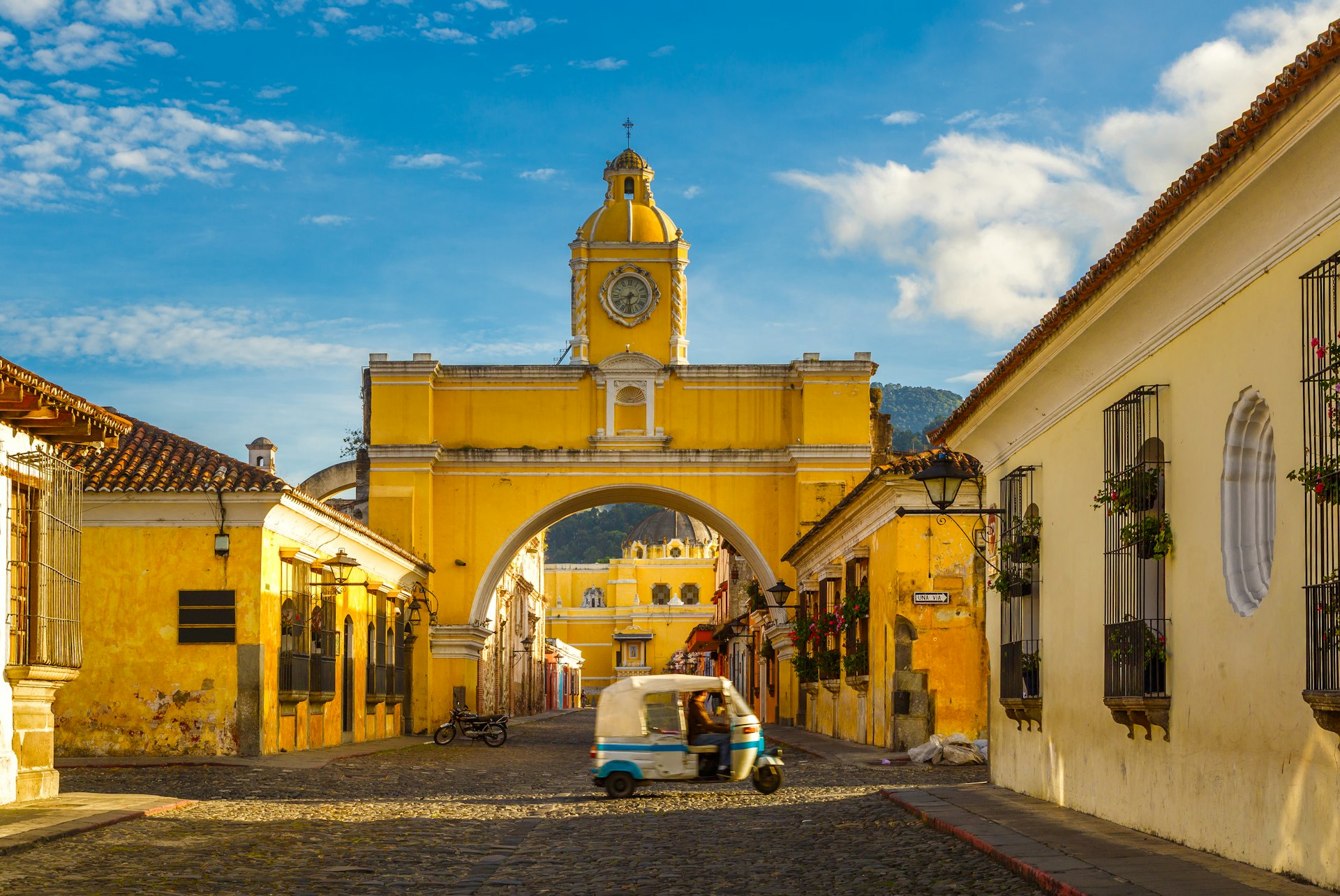 A tuk-tuk taxi passes the Arch of Santa Catalina in Antigua, Guatemala