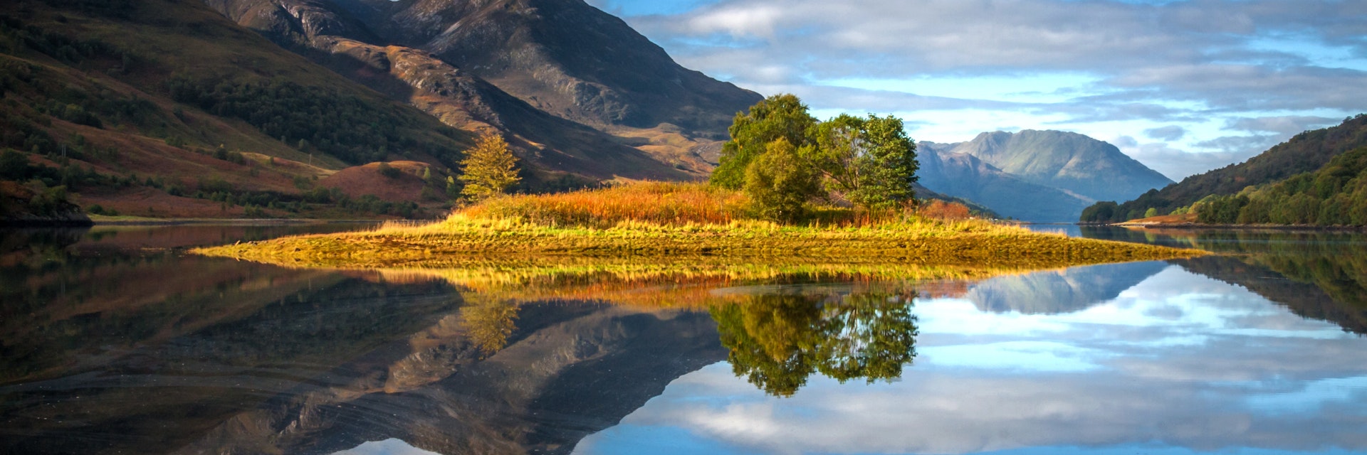 Reflections of the island in Loch Leven, Scotland, with the Pap of Glencoe in the middle distance.