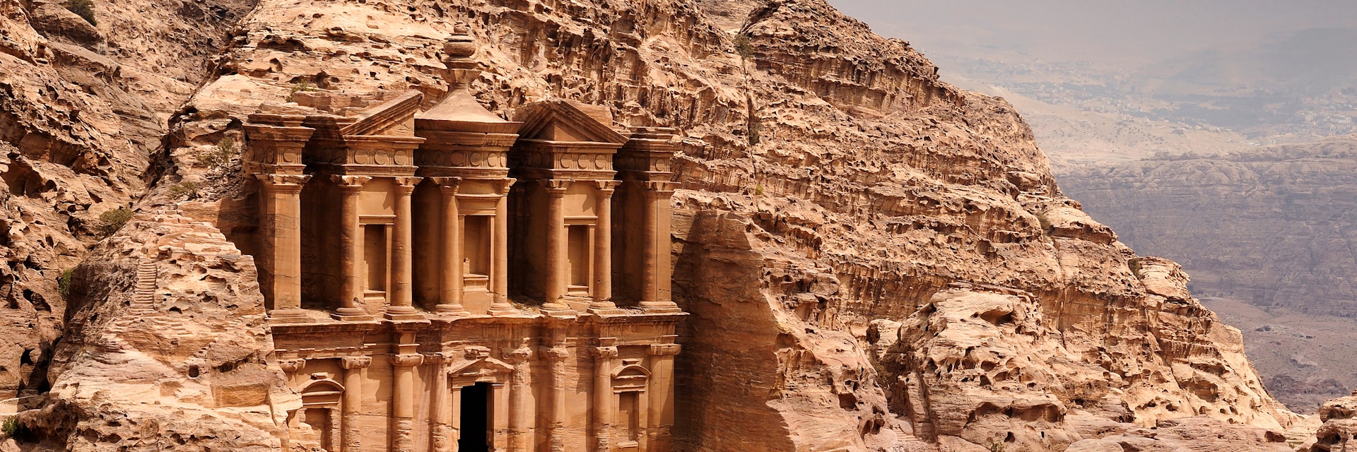 There is a person by the doorway to get a scale of the size. A classic view of El Deir, The Monastery in Petra. Shown in the context of the mountain that the facade was carved out of by the Nabataeans in the 1st century. The facade measures 50 metres wide by approximately 45 meters high.