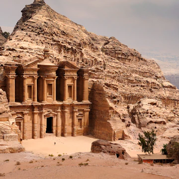 There is a person by the doorway to get a scale of the size. A classic view of El Deir, The Monastery in Petra. Shown in the context of the mountain that the facade was carved out of by the Nabataeans in the 1st century. The facade measures 50 metres wide by approximately 45 meters high.