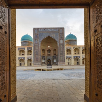 Blue domes of the Madressa through open wooden door in Bukhara, Uzbekistan.