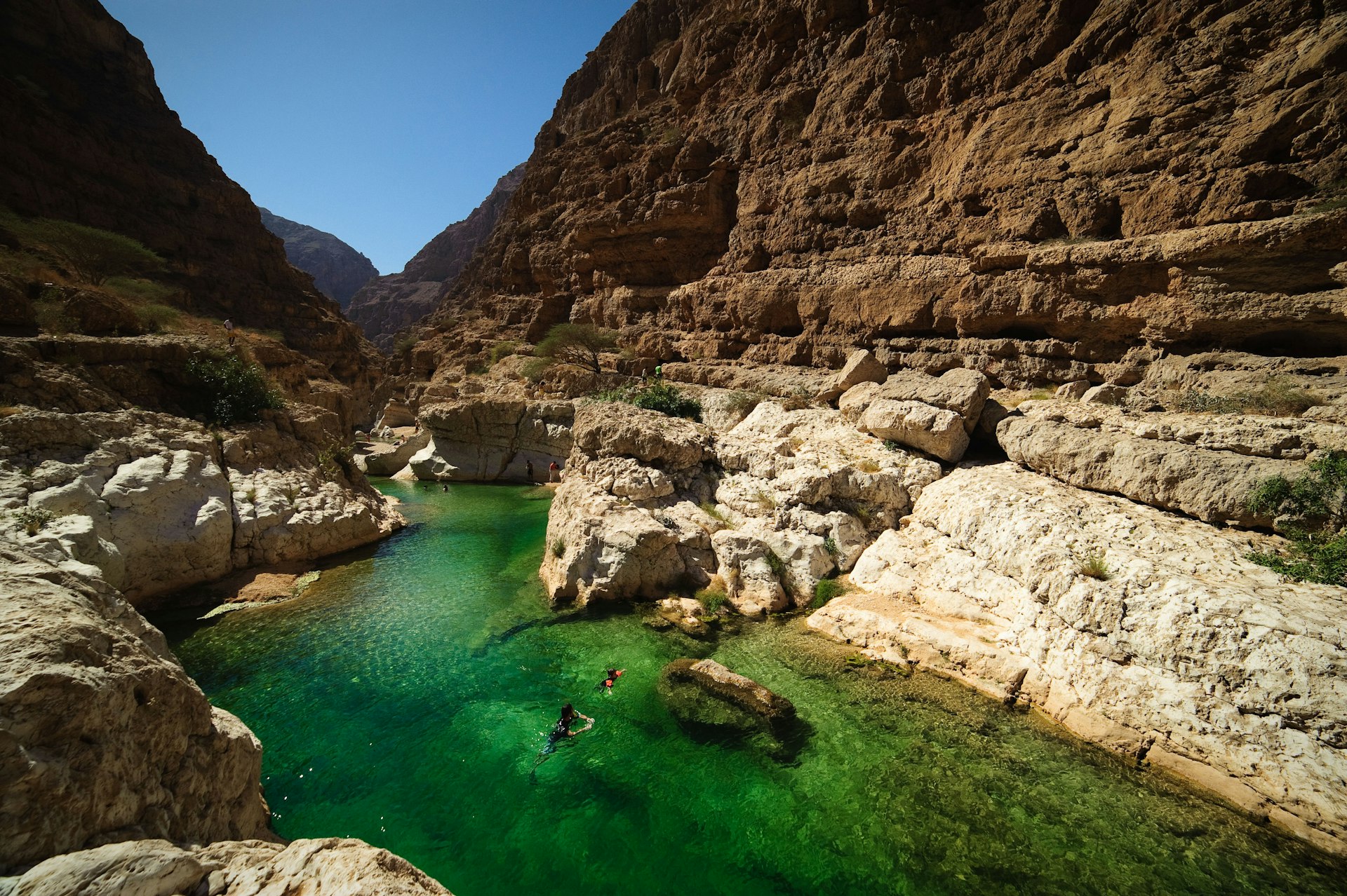 Two people swimming in the turqoise waters of Wadi Shab, Oman