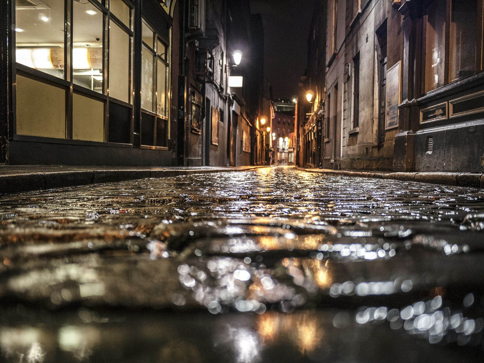 An empty dark cobbled alley shot from ground level at night
