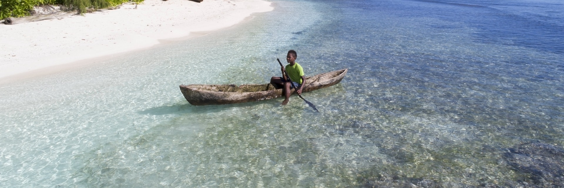 Child in a homemade wooden canoe in Papua New Guinea.