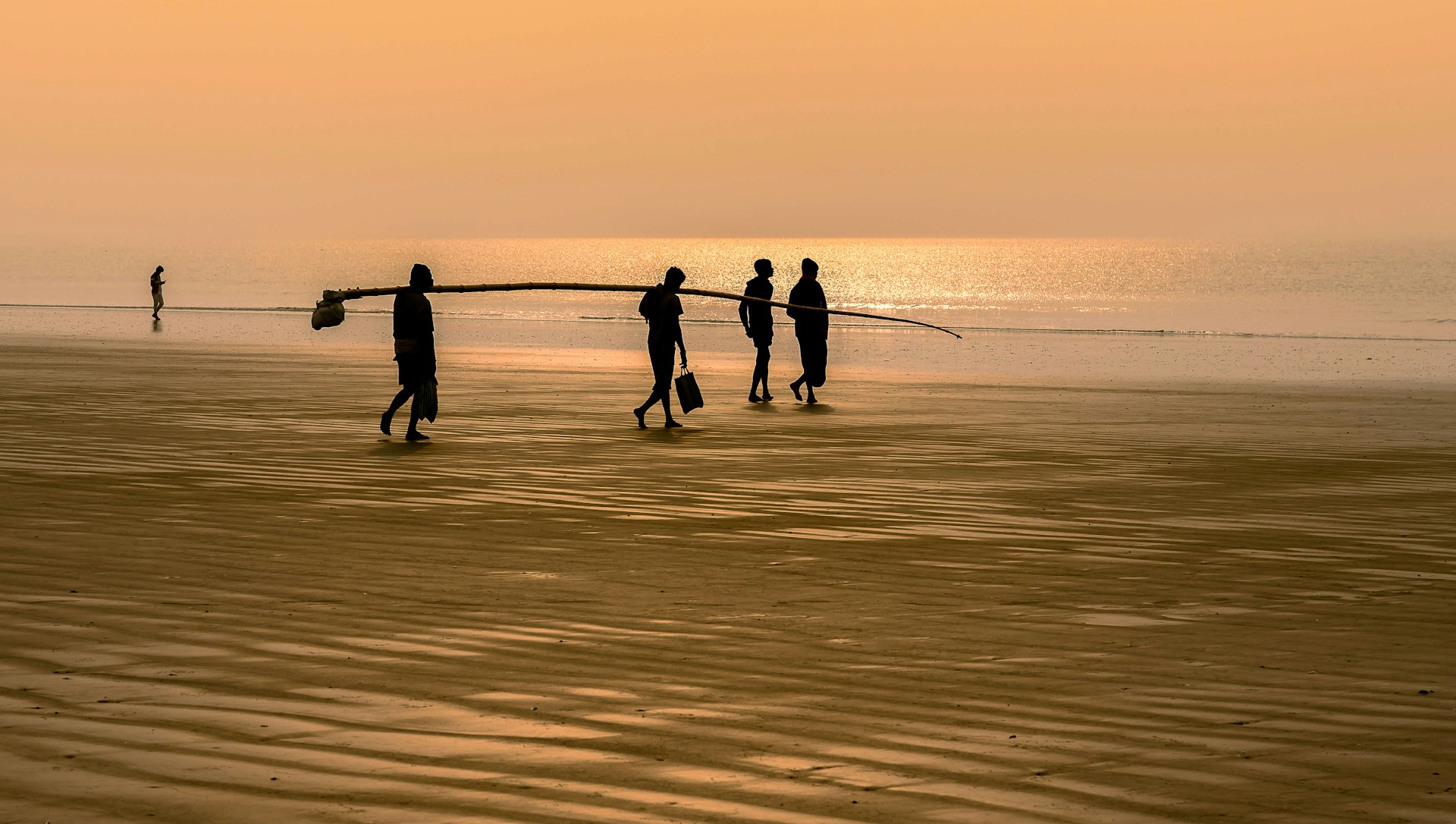 Silhouette of people walking on the beach at dusk
