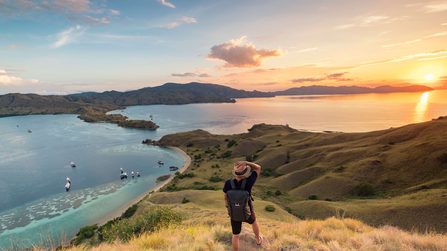 A man with his hand on his hat, looking out from Gili Lawa in Komodo National Park