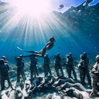 May 12, 2019. Gili Meno, Indonesia. Woman freediver with fins dive near underwater statues. Underwater tourism in the ocean.